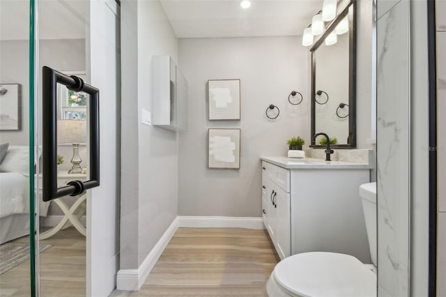 bathroom featuring baseboards, toilet, vanity, and wood finished floors