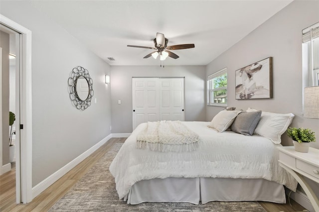 bedroom featuring a closet, visible vents, baseboards, a ceiling fan, and light wood-style floors