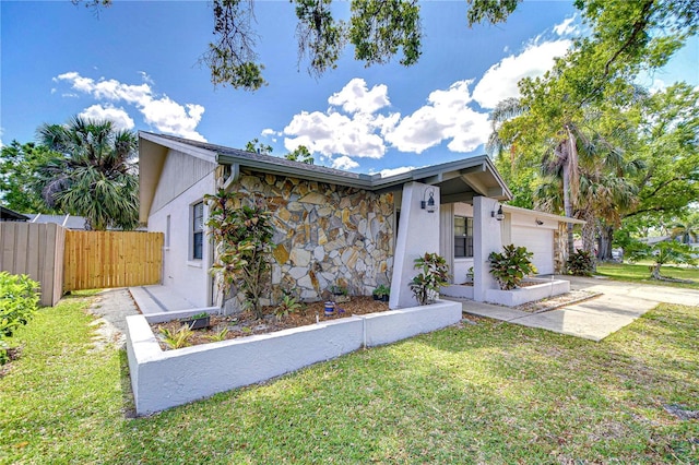4110 Summerdale Dr, Tampa, FL 33624 - mid-century modern home featuring stone siding, concrete driveway, fence, a front lawn, and a garage