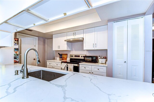 4110 Summerdale Dr, Tampa, FL 33624 - kitchen featuring stainless steel range with electric stovetop, under cabinet range hood, a sink, light stone counters, and white cabinets