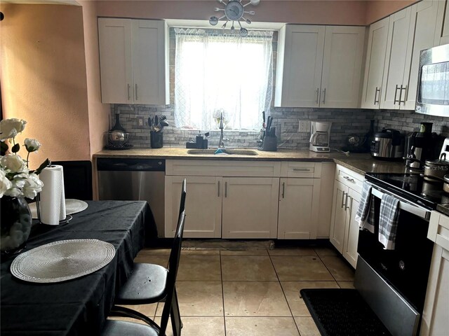 1312 Foxboro Dr, Brandon, FL 33511 - kitchen featuring light tile patterned flooring, a sink, backsplash, white cabinetry, and appliances with stainless steel finishes