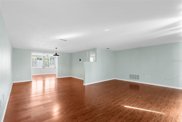spare room featuring baseboards, visible vents, and wood finished floors