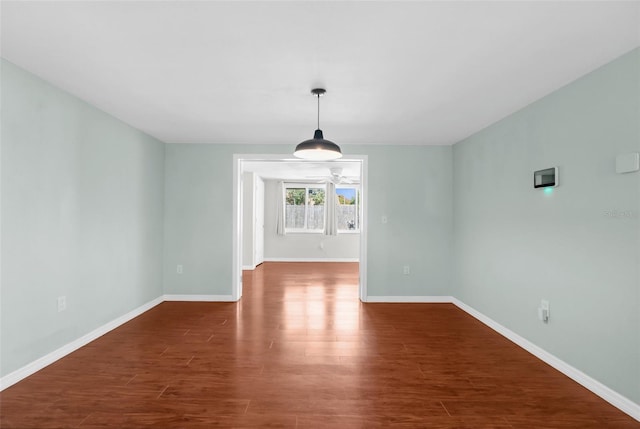 unfurnished dining area with dark wood finished floors and baseboards