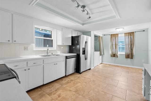 kitchen featuring white cabinets, appliances with stainless steel finishes, a raised ceiling, a sink, and backsplash