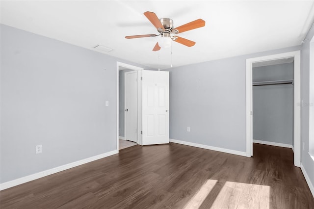unfurnished bedroom with baseboards, a spacious closet, wood finished floors, and a closet