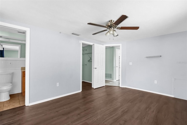 unfurnished bedroom featuring a closet, wood finished floors, a spacious closet, baseboards, and visible vents