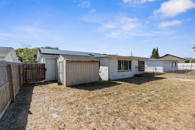 rear view of property featuring a fenced backyard, an outbuilding, a shed, and a lawn