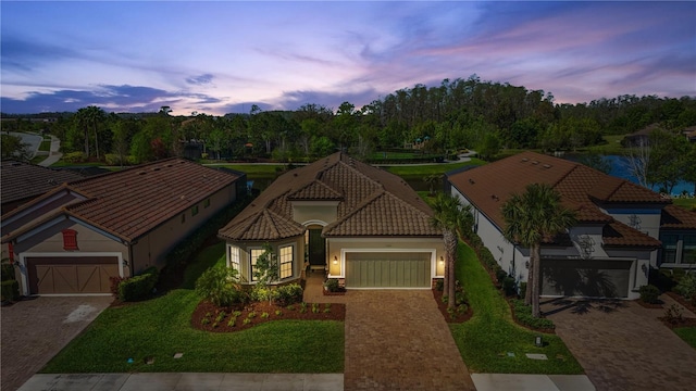 view of front of house featuring a tile roof, decorative driveway, a garage, and stucco siding