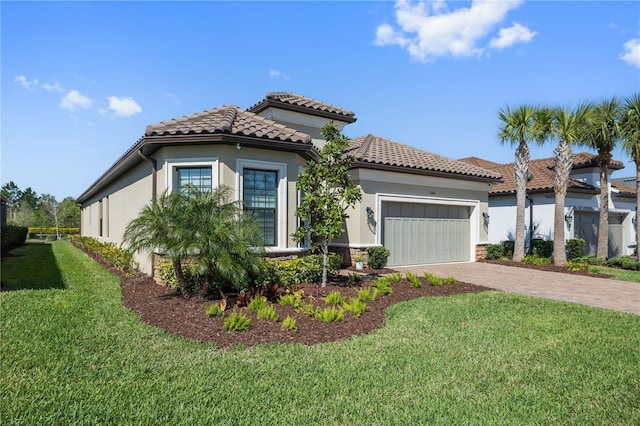 mediterranean / spanish-style home with driveway, stucco siding, a front yard, and a tile roof