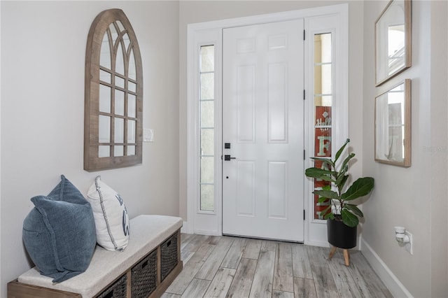 foyer entrance with plenty of natural light, baseboards, and light wood-style floors