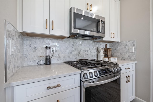 kitchen with white cabinetry, stainless steel appliances, light stone counters, and tasteful backsplash