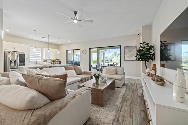living area featuring light wood-style flooring, recessed lighting, baseboards, and ceiling fan