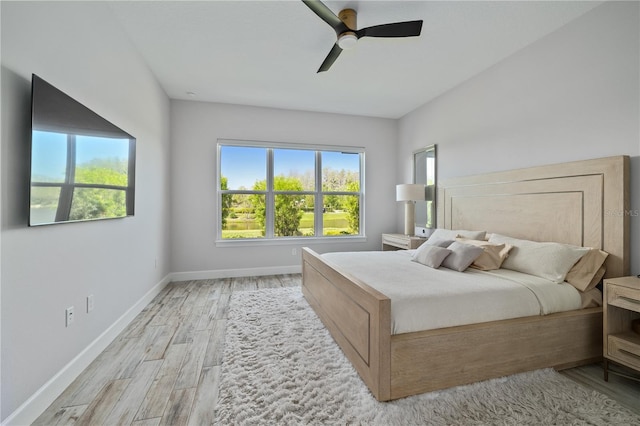 bedroom with baseboards, a ceiling fan, and light wood-type flooring