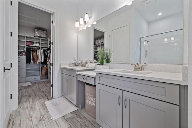 bathroom with vanity, wood finished floors, a walk in closet, and a shower stall