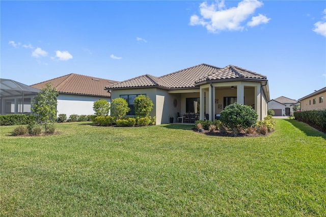 back of house with a lawn, stucco siding, and a tiled roof