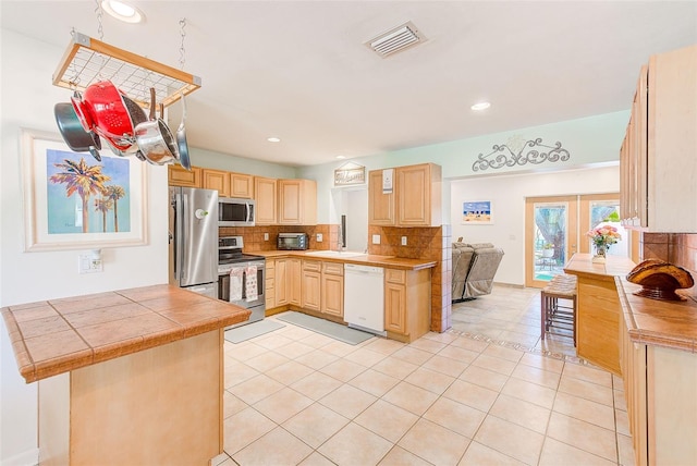 700 16th St NW, Largo, FL 33770 - kitchen with light tile patterned flooring, visible vents, decorative backsplash, light brown cabinets, and appliances with stainless steel finishes