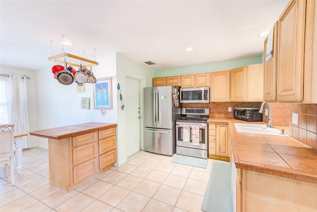 700 16th St NW, Largo, FL 33770 - kitchen featuring a peninsula, a sink, decorative backsplash, light brown cabinets, and appliances with stainless steel finishes