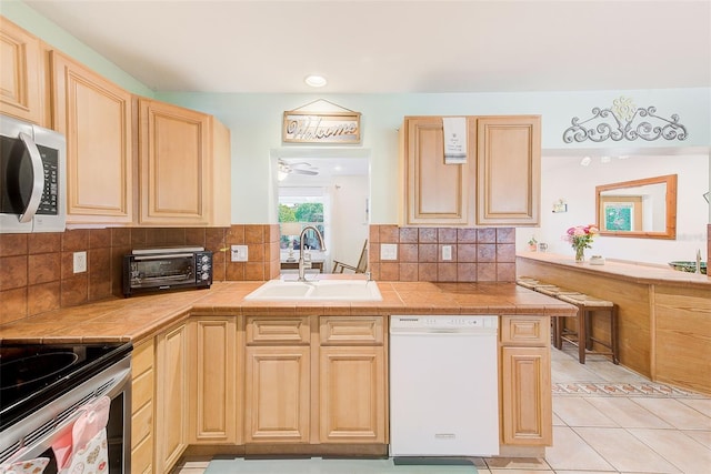 700 16th St NW, Largo, FL 33770 - kitchen featuring a toaster, light brown cabinets, a sink, tasteful backsplash, and appliances with stainless steel finishes