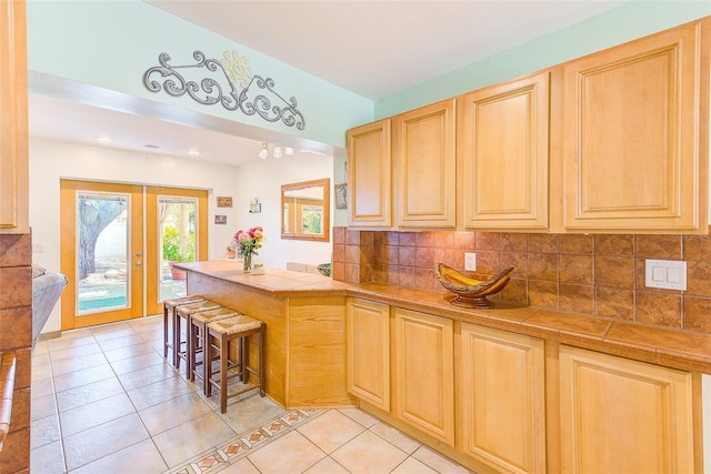 700 16th St NW, Largo, FL 33770 - kitchen featuring light brown cabinets, a peninsula, tasteful backsplash, and light tile patterned flooring