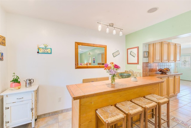 700 16th St NW, Largo, FL 33770 - kitchen with track lighting, a breakfast bar area, tasteful backsplash, and light tile patterned floors
