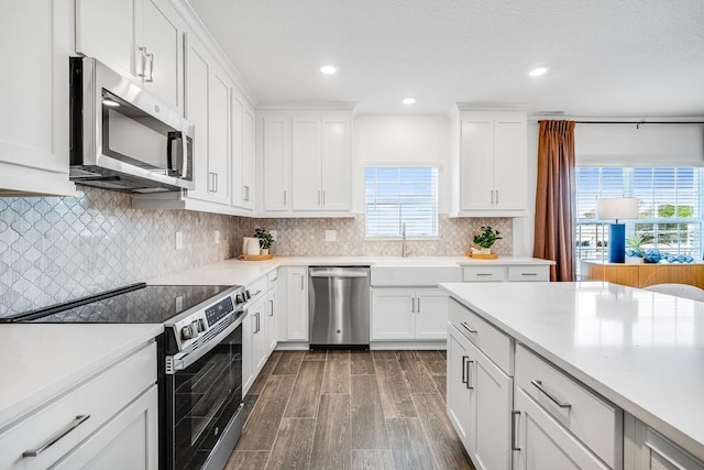 kitchen featuring appliances with stainless steel finishes, a sink, light countertops, and dark wood-style floors