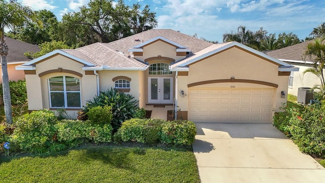 4942 Oldham St, Sarasota, FL 34238 - view of front of house featuring french doors, an attached garage, stucco siding, central AC unit, and concrete driveway
