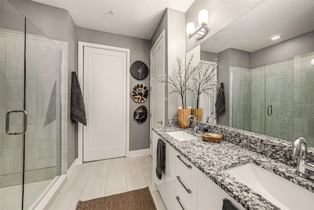 2511 N Grady Ave Unit 82, Tampa, FL 33607 - full bathroom featuring double vanity, a shower stall, a textured ceiling, baseboards, and tile patterned floors