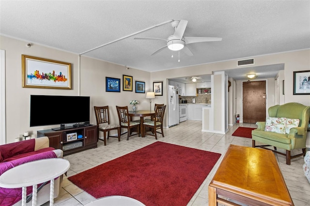 living area with a ceiling fan, light tile patterned floors, a textured ceiling, and visible vents