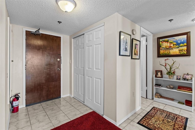 entryway featuring baseboards, a textured ceiling, and light tile patterned floors
