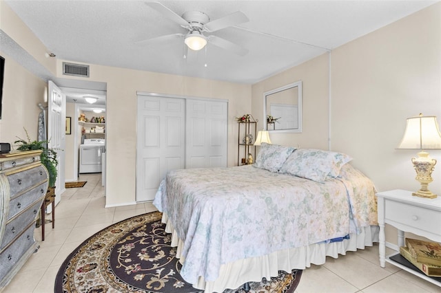 bedroom featuring light tile patterned flooring, a closet, visible vents, ceiling fan, and washer / dryer