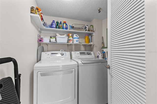 laundry area with washing machine and clothes dryer, a textured ceiling, and laundry area