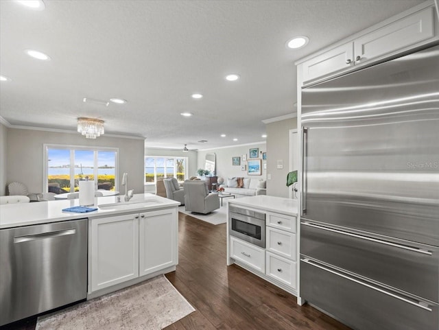 2087 Edgewater Dr Unit C, Clearwater, FL 33755 - kitchen with built in appliances, crown molding, dark wood-style flooring, white cabinetry, and open floor plan
