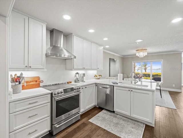 2087 Edgewater Dr Unit C, Clearwater, FL 33755 - kitchen with stainless steel appliances, wall chimney exhaust hood, ornamental molding, a peninsula, and white cabinetry