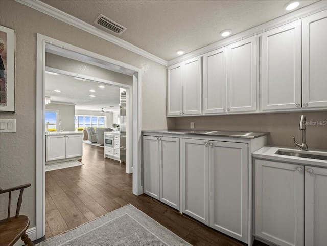 2087 Edgewater Dr Unit C, Clearwater, FL 33755 - kitchen with ornamental molding, dark wood-style flooring, a textured ceiling, white cabinets, and recessed lighting