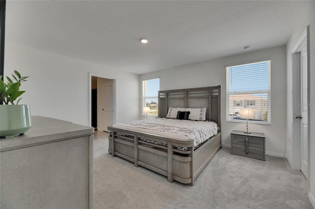 bedroom with baseboards, light colored carpet, and a textured ceiling