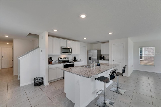 kitchen with light tile patterned floors, a sink, a breakfast bar area, and appliances with stainless steel finishes