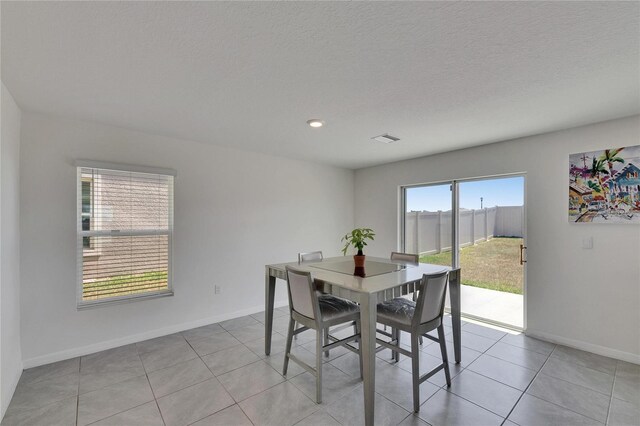 dining area featuring visible vents, baseboards, a textured ceiling, and light tile patterned flooring