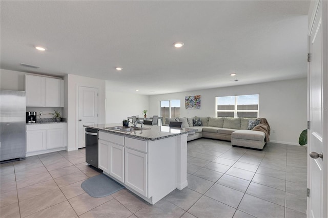 kitchen featuring stone counters, stainless steel refrigerator, white cabinetry, dishwasher, and a sink