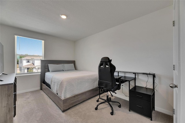 bedroom with a textured ceiling, light colored carpet, and baseboards