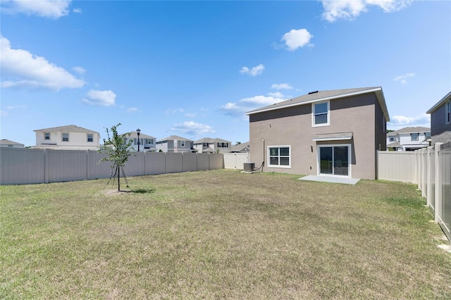rear view of property featuring a yard, a residential view, a fenced backyard, and stucco siding