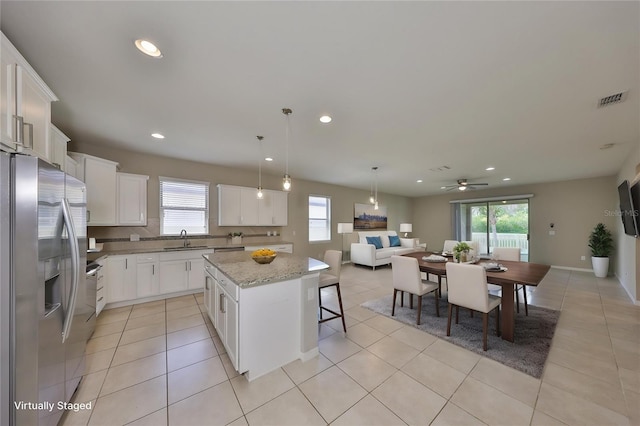 kitchen with visible vents, plenty of natural light, a center island, and stainless steel fridge with ice dispenser