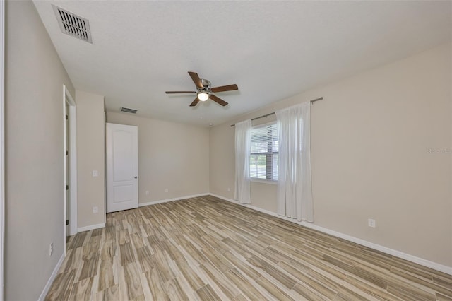 unfurnished room featuring ceiling fan, visible vents, baseboards, and light wood-type flooring