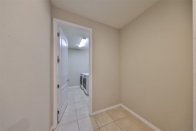 corridor featuring light tile patterned floors, baseboards, and independent washer and dryer