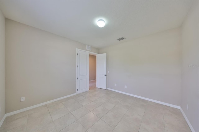 unfurnished room featuring baseboards, visible vents, and light tile patterned floors