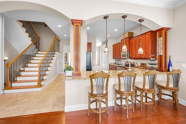 47 W Morgan St, Tarpon Springs, FL 34689 - kitchen featuring appliances with stainless steel finishes, light stone countertops, a sink, a peninsula, and ornate columns