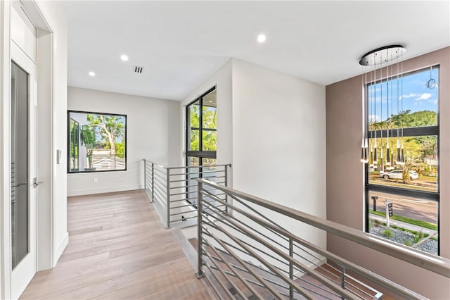 hall with light wood finished floors, visible vents, an upstairs landing, and recessed lighting