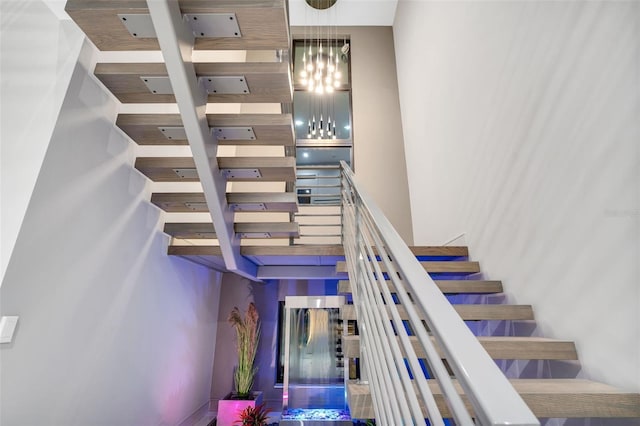 stairs featuring a towering ceiling and a notable chandelier