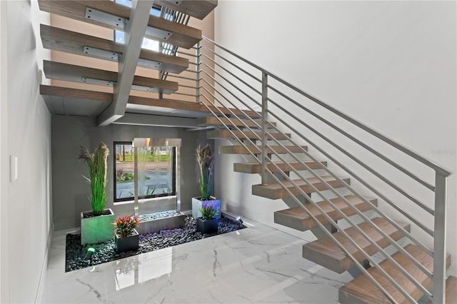 staircase with marble finish floor and a towering ceiling