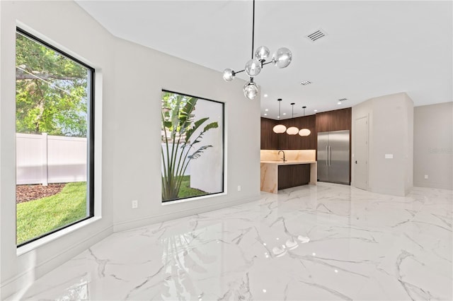 unfurnished living room featuring marble finish floor, a sink, a healthy amount of sunlight, and visible vents