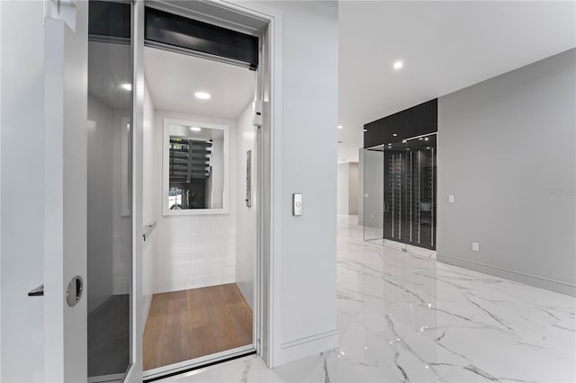 corridor with marble finish floor, baseboards, and recessed lighting